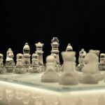 Close-up of a glass chess set with a reflection, emphasizing strategy and elegance.