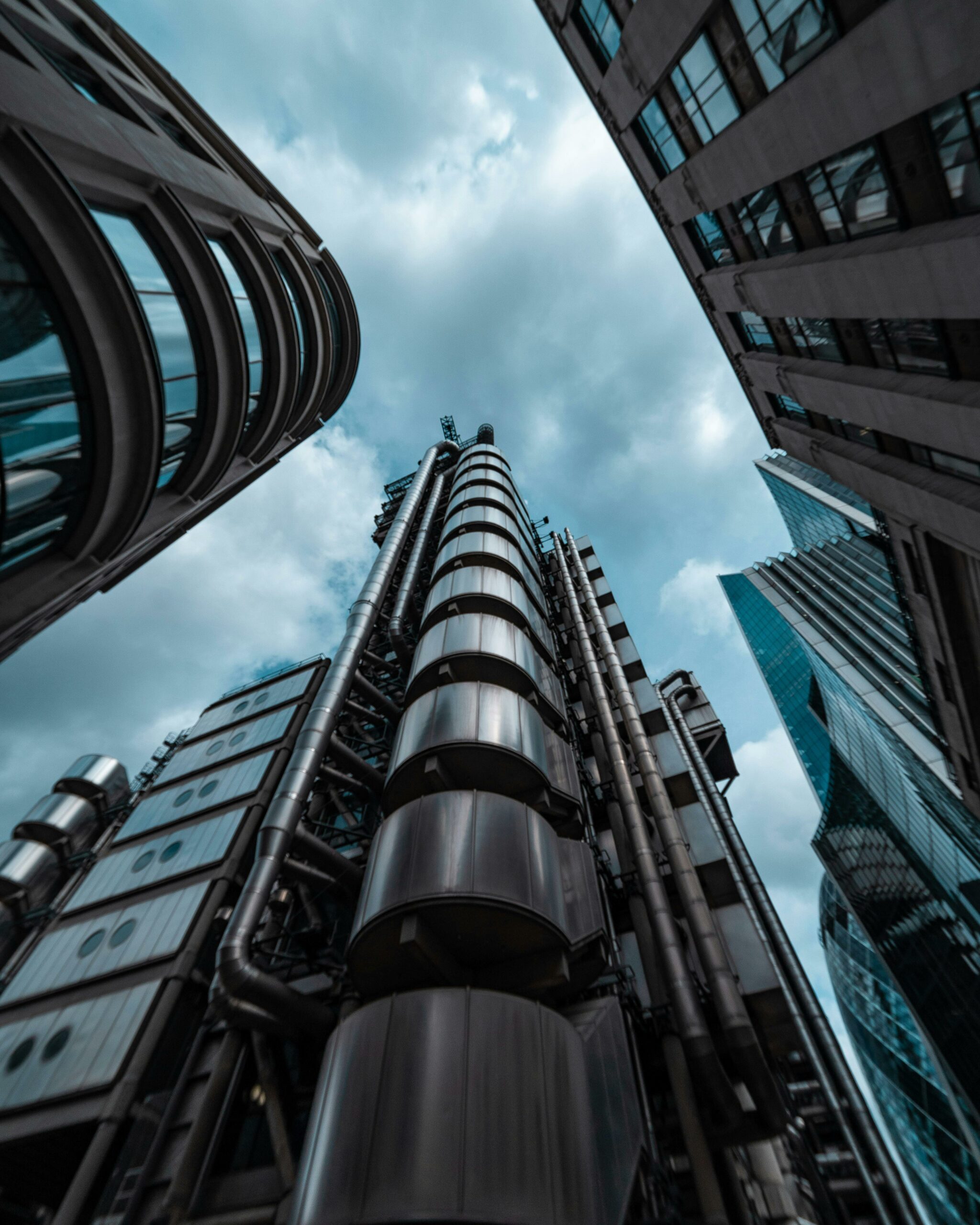 Dramatic low-angle shot of London's modern skyscrapers against a cloudy sky.