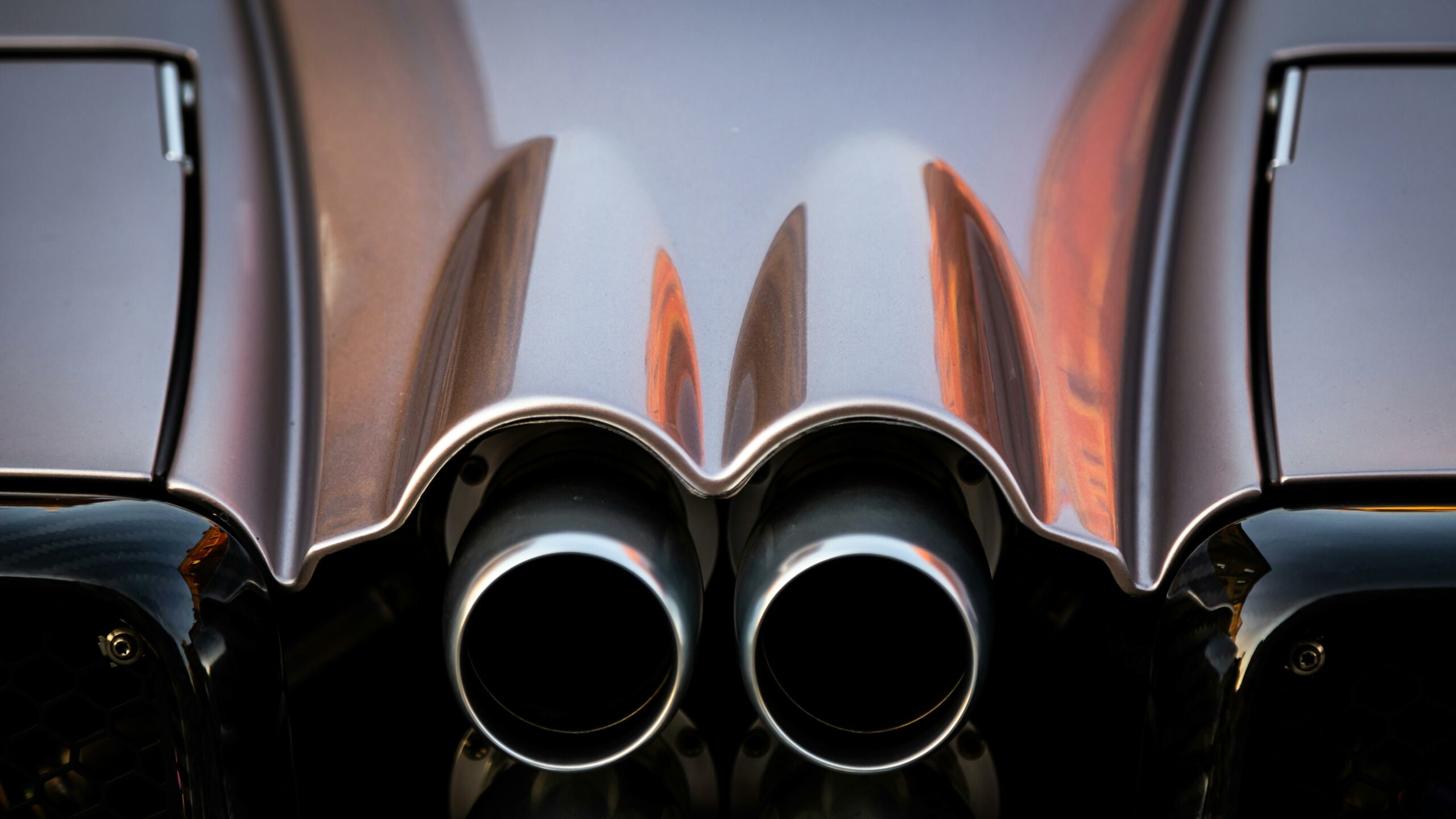 Detailed close-up of twin exhaust pipes on a luxury sports car showcasing sleek design and elegance.
