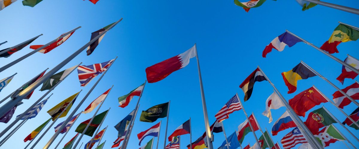 pexels-photo-14676984-14676984 International flags waving against a clear blue sky in Doha, Qatar, symbolizing unity and diversity.
